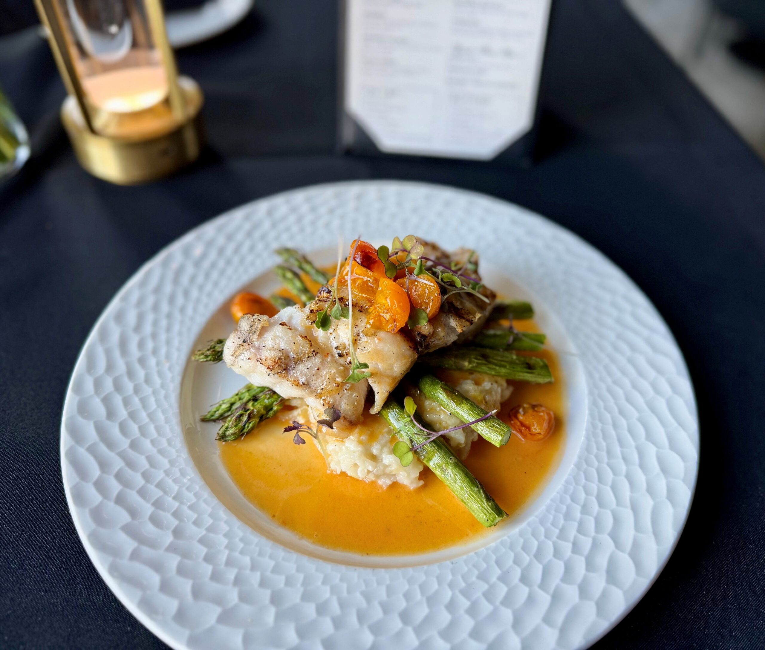 Grilled red grouper with local asparagus, Parmesan risotto, Calabrian chili beurre blanc, and roasted tomatoes at Cellar & Flame in Traverse City
