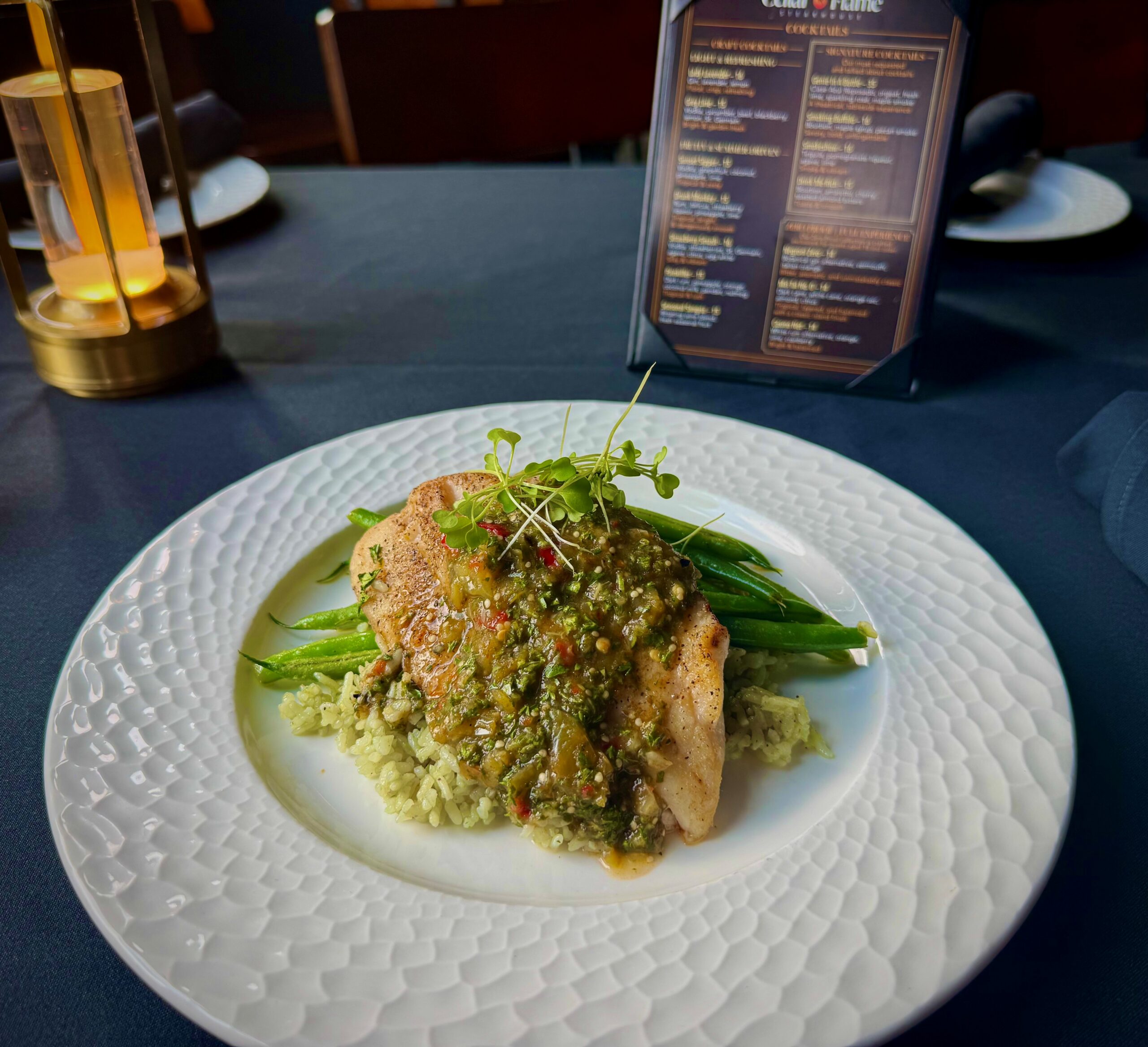 Pan-seared spotted rose snapper served over bamboo rice pilaf with green beans and Calabrian chili verde sauce at Cellar & Flame in Traverse City.