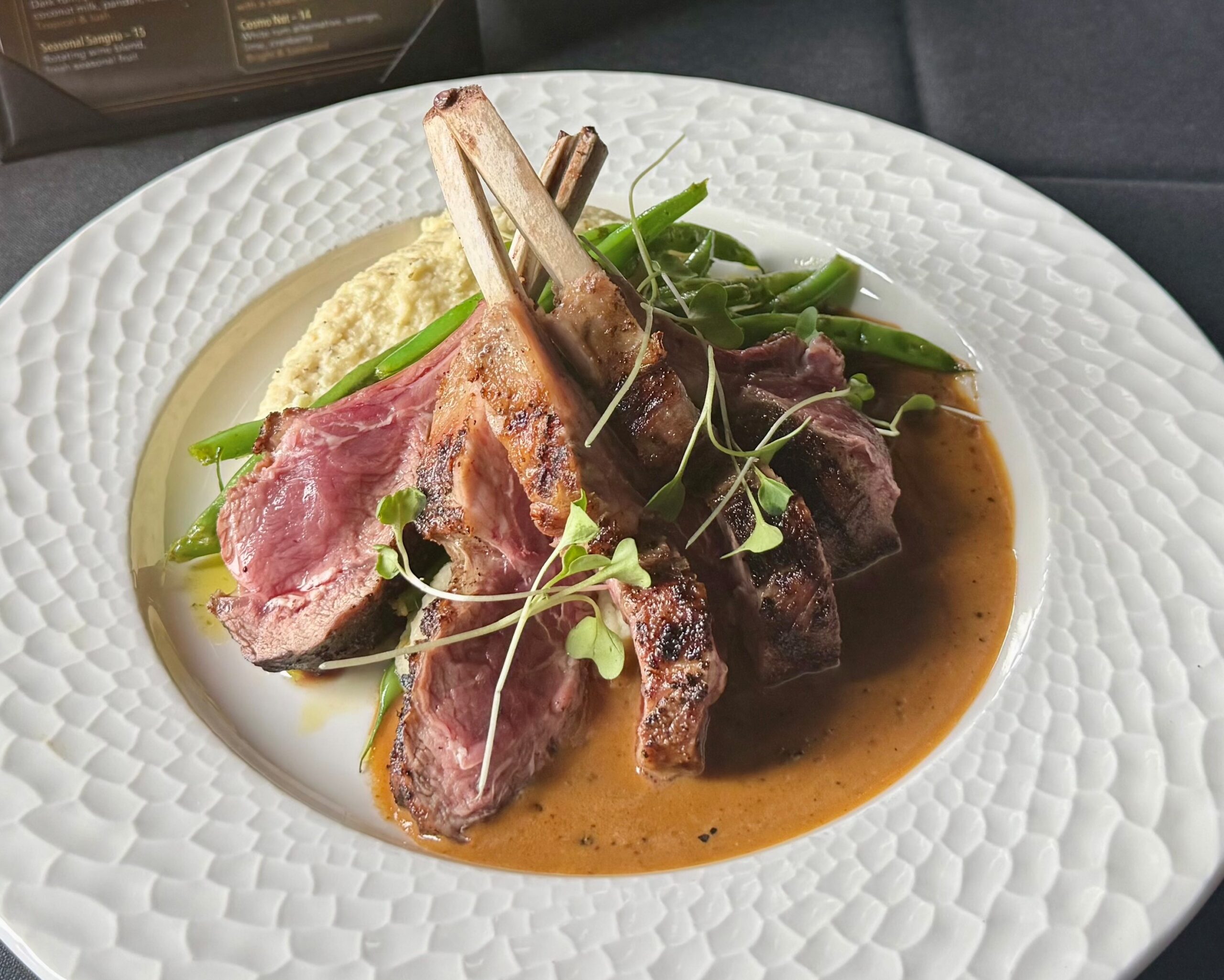 New Zealand half rack of lamb with parsnip purée, green beans, and au poivre sauce at Cellar & Flame Steakhouse in Traverse City