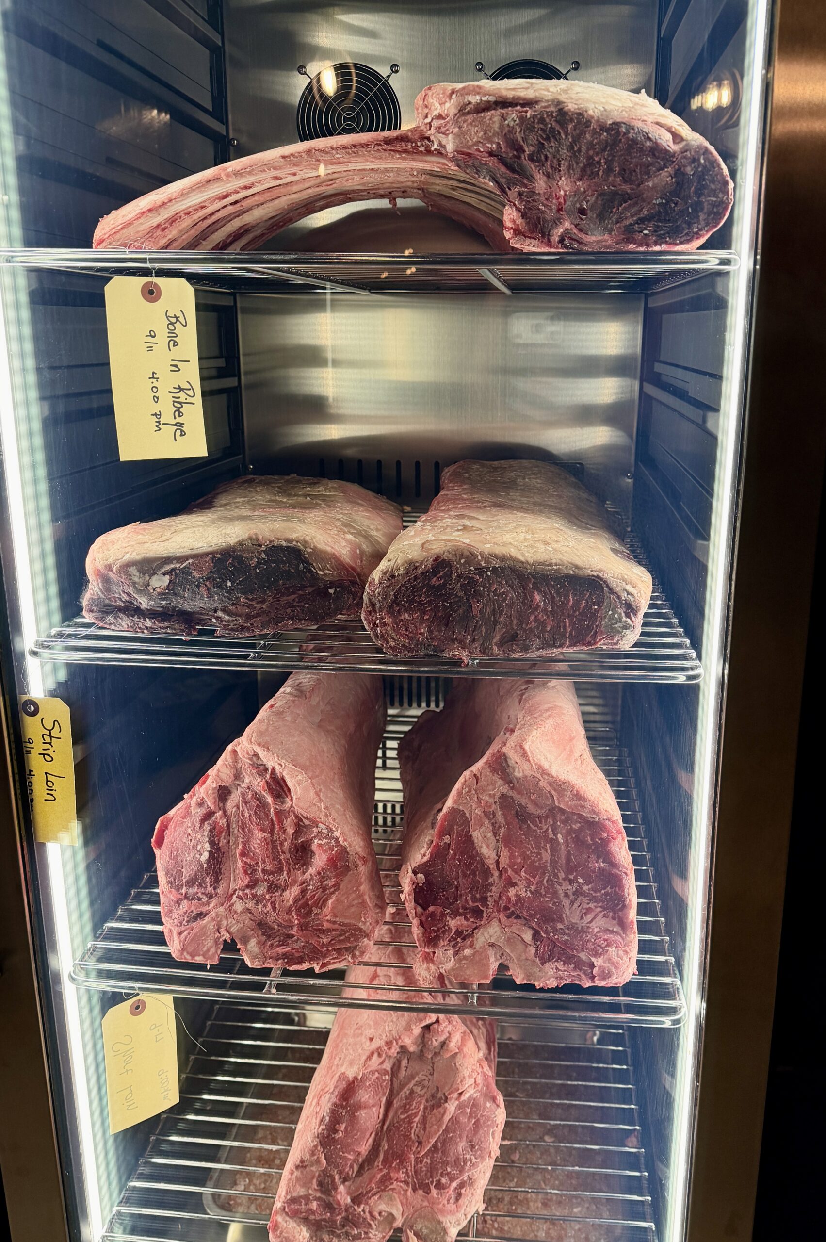 Tomahawks and Prime short loins aging inside the Cellar & Flame dry-aging cabinet in Traverse City.