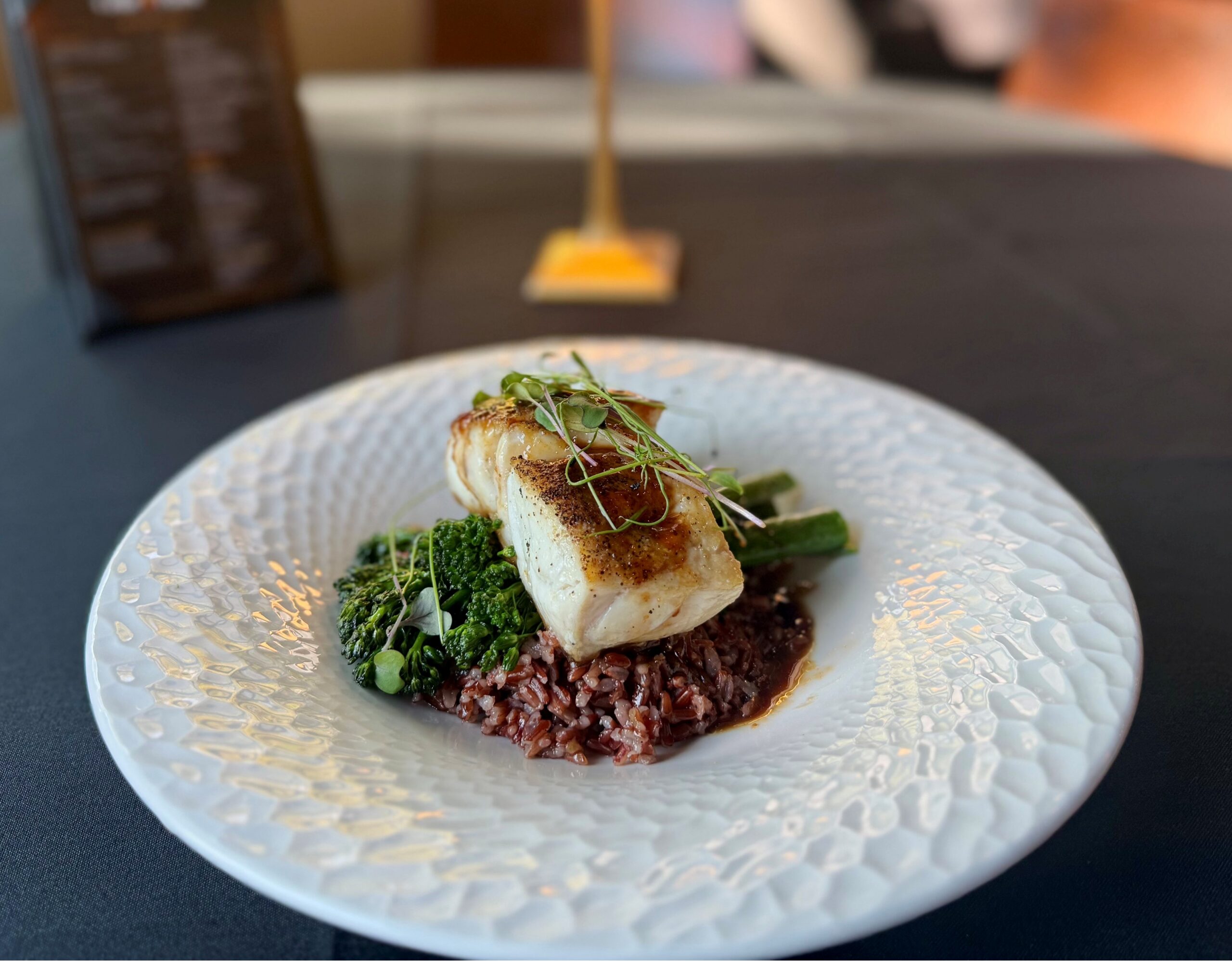 Black grouper served over red rice with broccolini and red miso hot honey at Cellar & Flame in Traverse City.